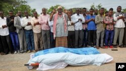 FILE - Mourners pray over the bodies of journalists Mohamed Abdikarim Moallim Adam, a reporter for the London-based Universal television, and Abdihakin Mohamed Omar, a producer for the Somali Broadcasting Corporation, at their funeral in Mogadishu, Somalia, July 27, 2015. 