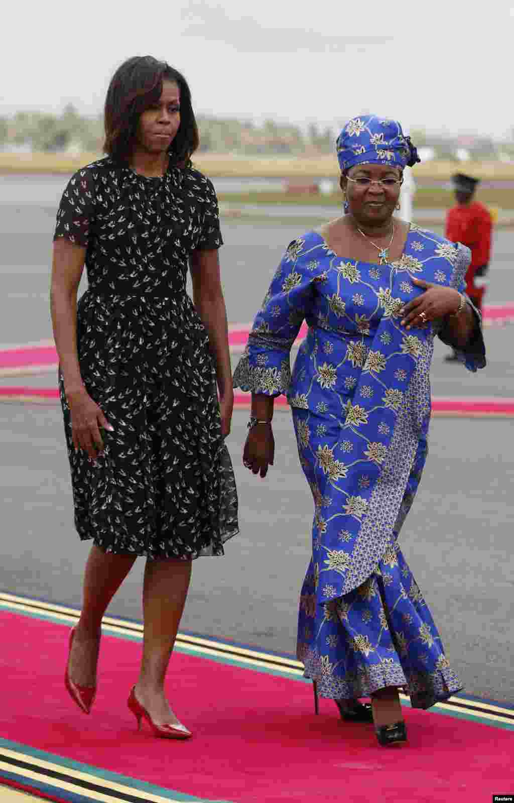 U.S. First lady Michelle Obama walks with Salma Kikwete, wife of Tanzania&#39;s president, during a departure ceremony in Dar es Salaam, July 2, 2013. 