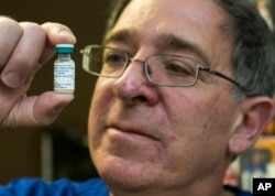 FILE - Pediatrician Charles Goodman holds a dose of the measles-mumps-rubella vaccine, or MMR vaccine at his practice in Northridge, California, Jan. 29, 2015.
