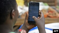 Une femme passe en revue son compte WhatsApp sur son téléphone, à Kampala, le 5 juillet 2018.