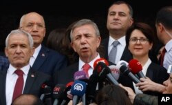 The main Turkish opposition candidate for the country's capital Ankara, Mansur Yavas, center, speaks to the media after he received the document confirming him as new mayor, from Bahattin Ozbas the head of the election board, in Ankara on April 8, 2019.