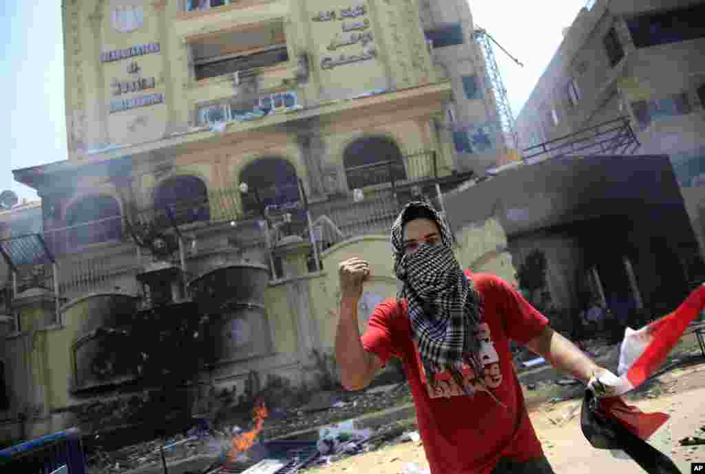 A protester holds an Egyptian national flag as he and others attack the Muslim Brotherhood headquarters in the Muqattam district in Cairo, July 1, 2013.