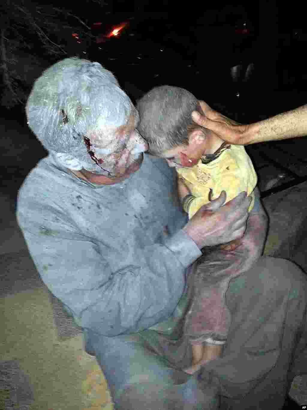 This citizen journalism image shows a wounded Syrian man holding his injured son after an air raid on the northwestern town of Saraqeb in the province of Idlib, Syria, April 25, 2013. (Edlib News Network ENN)