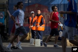 FILE - Municipal workers, most often migrants from former Soviet states or Central Asian countries, stand ready to clean at Moscow's Luzhniki Stadium in Moscow, Russia, June 26, 2018.