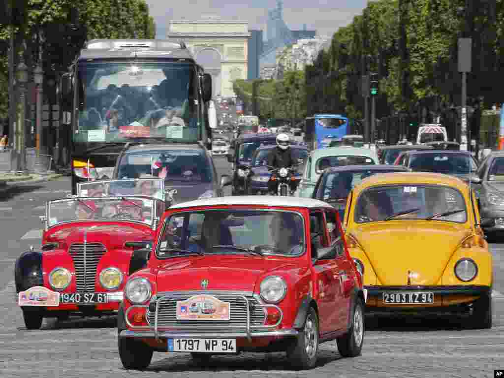 A parade of hundreds of classic cars makes its way along the Champs Elysee Avenue in Paris, France, during the Summer Crossing Paris 2014 event.