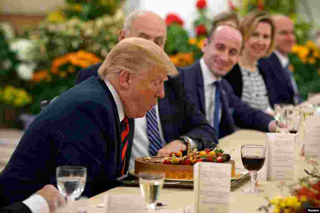 U.S. President Donald Trump blows out the candle on his birthday cake as he attends a lunch with Singapore's Prime Minister Lee Hsien Loong at the Istana in Singapore.