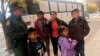 FILE - A migrant family from Central America waits outside the Annunciation House shelter in El Paso, Texas, after a U.S. Immigration and Customs Enforcement officer drops them off, Nov. 29, 2018. 