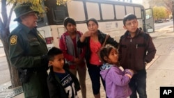 FILE - A migrant family from Central America waits outside the Annunciation House shelter in El Paso, Texas, after a U.S. Immigration and Customs Enforcement officer drops them off, Nov. 29, 2018. 