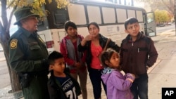 FILE - A migrant family from Central America waits outside the Annunciation House shelter in El Paso, Texas, after a U.S. Immigration and Customs Enforcement officer drops them off, Nov. 29, 2018. 