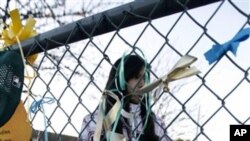 A student plays near a make-shift memorial at Mesa Verde Elementary School, where Christina Taylor Green was a third-grader, in Tucson, Ariz., 11 Jan 2011