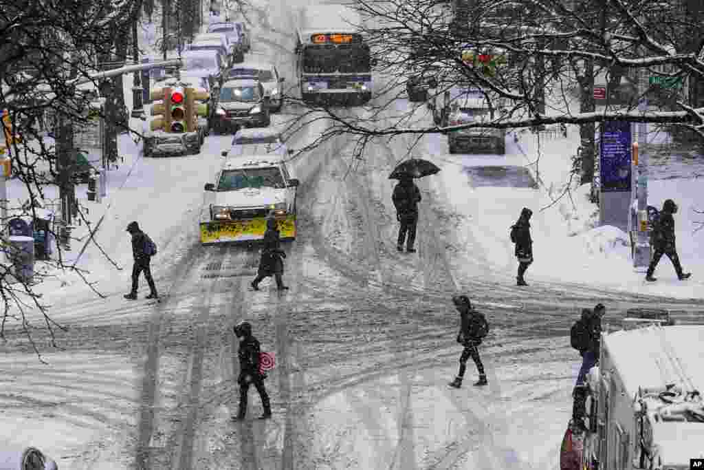 Pedestrians cross 71st Avenue as snow falls in the Queens borough of New York.