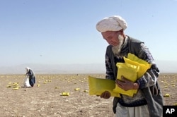 FILE - Local Afghan residents pick up food packets of U.S. humanitarian aid dropped by U.S. planes in a field near Khwaja-Bahauddin, anti-Taliban stronghold in northern Afghanistan, Oct. 13, 2001.