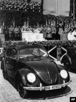 Nazi leader Adolf Hitler speaks prior to laying the cornerstone for a giant automobile factory in Fallersleben near Hanover, Germany, May 26, 1938. In the foreground is a Beetle car. (AP Photo)