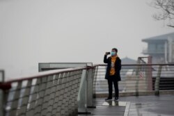 A man takes a photo at an overlook in Wuhan, in central China's Hubei Province, Jan. 22, 2022.