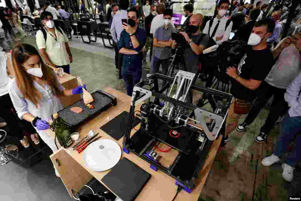 A woman cooks a piece of meat that was printed with a 3D printer by Novameat during the Mobile World Congress (MWC) in Barcelona, Spain, June 29, 2021.