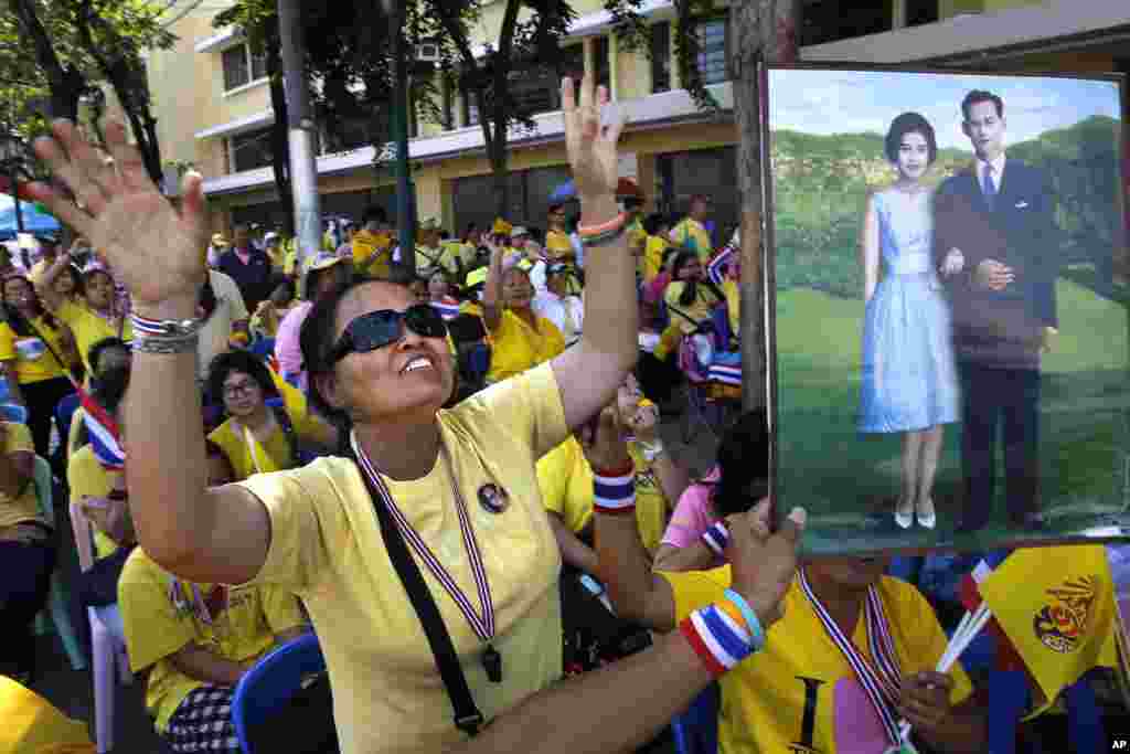 Thai people dressed in the royal color of yellow cheer as they watch their King Bhumibol Adulyadej make a speech on a giant screen, on his 86th birthday at the Democracy Monument in Bangkok, Dec. 5, 2013. 