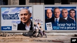 FILE - People walk by election campaign billboards showing Israeli Prime Minister Benjamin Netanyahu, left, alongside the Blue and White party leaders, from left to right, Moshe Yaalon, Benny Gantz, Yair Lapid and Gabi Ashkenazi, in Tel Aviv, Israel, April 3, 2019.