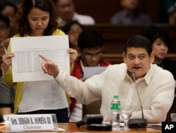 FILE - Philippine Sen. Teofisto Guingona III shows a document during hearings into how about $81 million of Bangladesh's stolen funds were transmitted online to four private accounts at a branch of the Rizal Commercial Banking Corp.