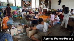 A family packs relief foods sent by relatives at a school building turned into an evacuation center in Loboc town, Bohol province on Dec. 21, 2021, days after super Typhoon Rai devastated the province. 