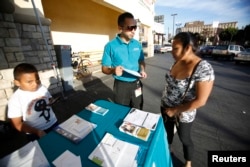 FILE - Jaime Corona, patient care coordinator at AltaMed, speaks to a woman during a community outreach on Obamacare in Los Angeles, Nov. 6, 2013.
