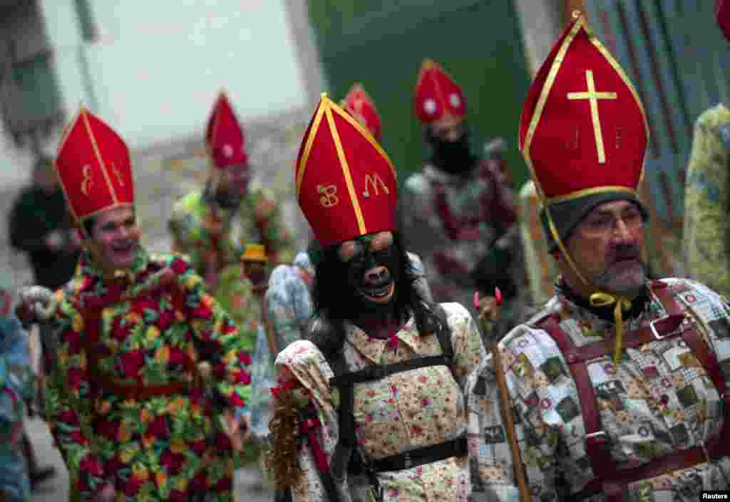 O crente Benito Martinez (ao centro) vestido de &quot;diabo&quot; usa uma máscara, caminha ao longo do Almonacid del Marquesado, em Cuenca, Espanha, no festival tradicional &quot;Endiablada&quot;.&nbsp; O festival tradicional honra o São Blas. fev. 3, 2014