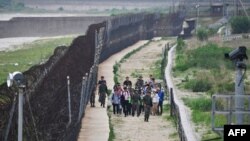 Para tentara Korea Selatan mengawal para pengunjung berjalan menyusuri zona demiliterisasi (DMZ) antara dua Korea yang dipisahkan pagar, Goseong, 14 Juni 2019. 