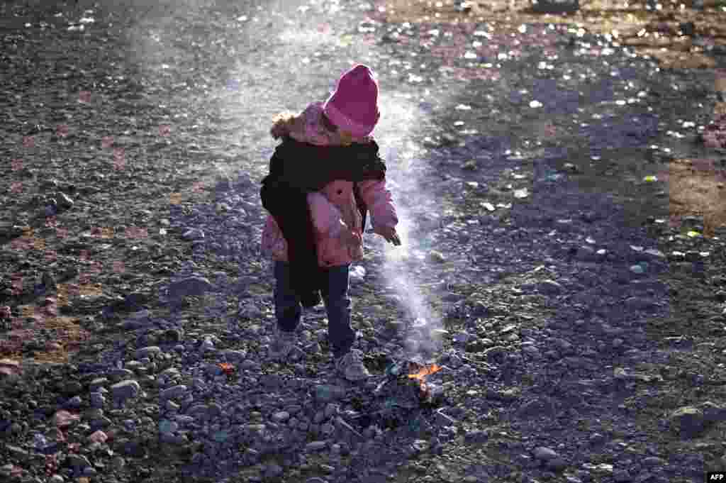 A girl warms up next to a small fire as migrants and refugees prepare to enter a registration camp after crossing the Greece-Macedonia border near Gevgelija. More than 218,000 migrants and refugees crossed the Mediterranean to Europe in October.