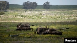 FILE- Israeli soldiers walks beside mobile artillery units near the city of Katzrin in the Golan Heights, March 19, 2014.
