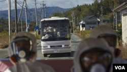 Para pejabat Jepang dan wartawan, dengan mengenakan masker dan pakaian pelindung, mengunjungi kompleks PLTN Fukushima yang lumpuh akibat tsunami (12/11).