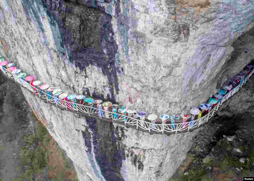 Women wearing cheongsam pose for pictures on a walkway along a cliff during an event in Chongqing Municipality, China, March 26, 2017.