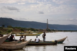 FILE - Fishermen row their boats next to an oil exploration site in Bulisa district, approximately 244 kilometers northwest of Kampala in this undated handout photo from Tullow Oil Uganda, July 2012.