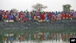 Displaced women gather to collect water from a water hole near Jamam refugee camp in South Sudan's Upper Nile State, March 10, 2012.