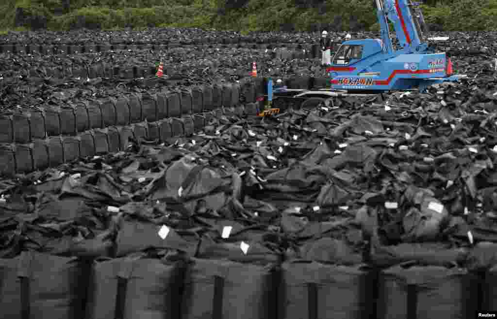 Công nhân chuyển những bao rác thải chứa đất, lá và những mảnh vụn bị nhiễm phóng xạ tại một khu chứa thuộc thị trấn Naraha, nằm trong vùng cấm qua lại trong vòng 20 kilômét đường kính chung quanh nhà máy điện hạt nhân Fukushima Daiichi đã ngưng hoạt động và hiện được chỉ định là một khu vực di tản, tại tỉnh Fukushima, Nhật Bản.