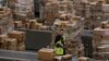 Workers walk past boxes to be shipped inside of an Amazon fulfillment center in Robbinsville, New Jersey, Nov. 27, 2017.