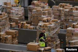 FILE - Workers walk past boxes to be shipped inside of an Amazon fulfillment center in Robbinsville, New Jersey, Nov. 27, 2017.