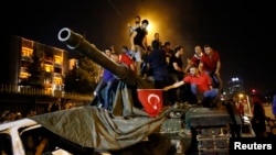 People stand on a Turkish army tank in Ankara, Turkey, July 16, 2016. 