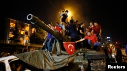 People stand on a Turkish army tank in Ankara, Turkey, July 16, 2016. 