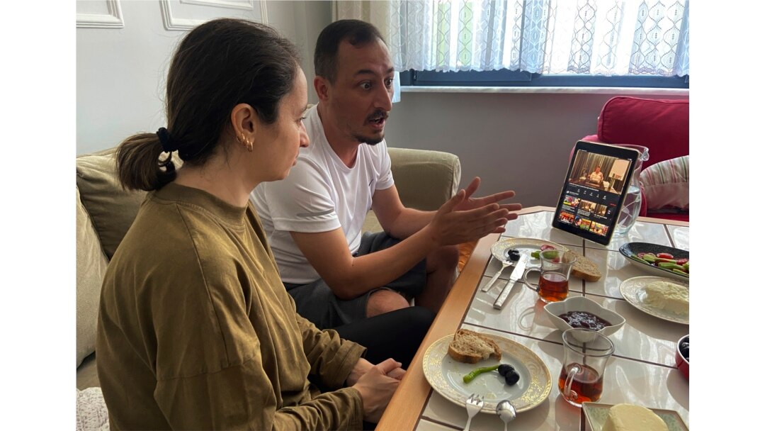 Alparslan Atas (41, tengah), berbicara dengan istrinya Gulistan (38, kiri) saat sarapan di rumah mereka di Istanbul, sambil menonton tayangan video Sedat Peker, bos kriminal buronan Turki di tablet mereka, Minggu, 6 Juni, 2021. (AP)
