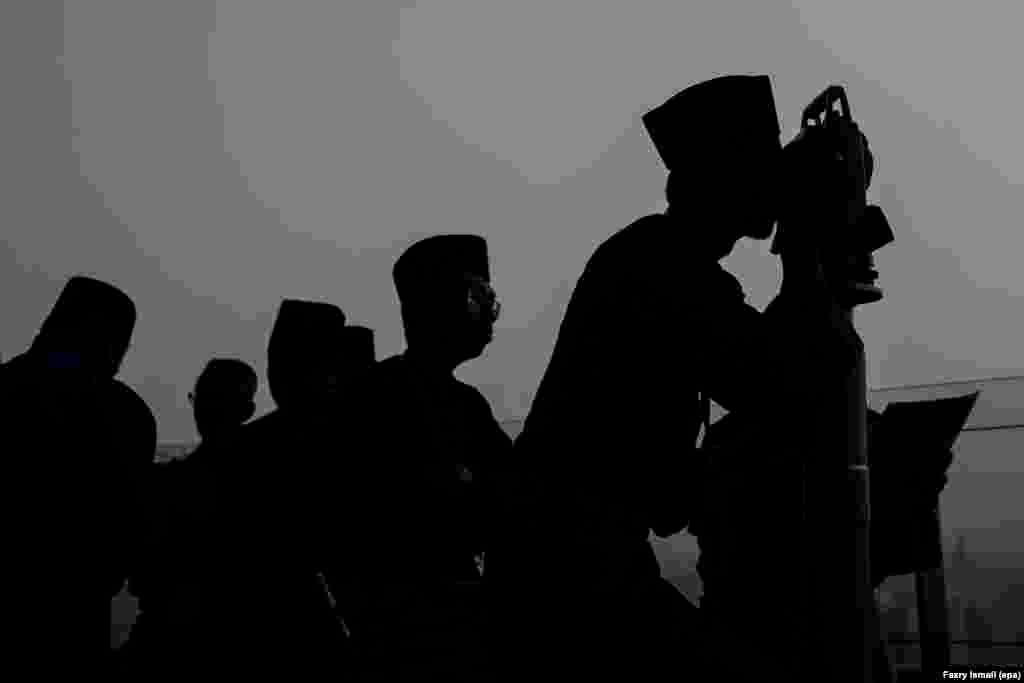 Para Muslim mengamati posisi bulan dengan alat teodolit untuk menentukan hari akhir bulan Ramadan, atau hari raya Idul Fitri di Kuala Lumpur, Malaysia.