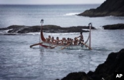 FILE - Aboriginal men of the Tao tribe take a newly launched fishing boat on a maiden voyage during a fishing boat launching ceremony on Orchid Island, Taiwan.