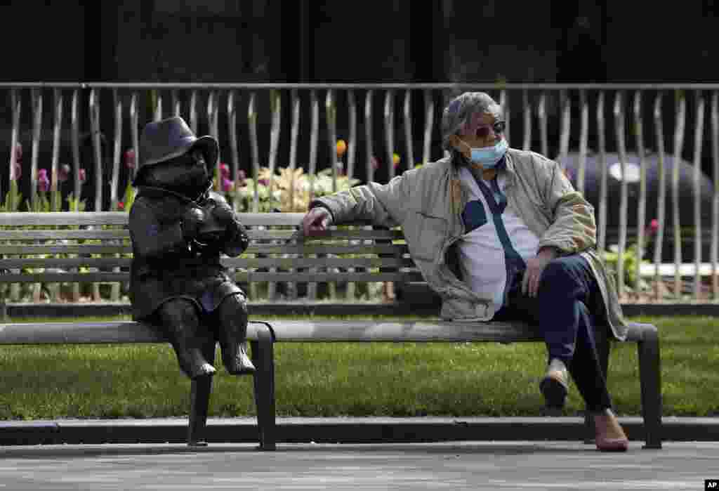 A man sits down on a bench in London next to a sculpture of Paddington Bear, as the country is in lockdown to help slow the spread of the coronavirus.
