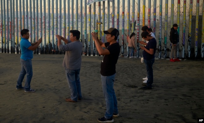 Personas graban con sus teléfonos el muro que separa Tijuana, México de Estados Unidos, el jueves 10 de enero de 2019.