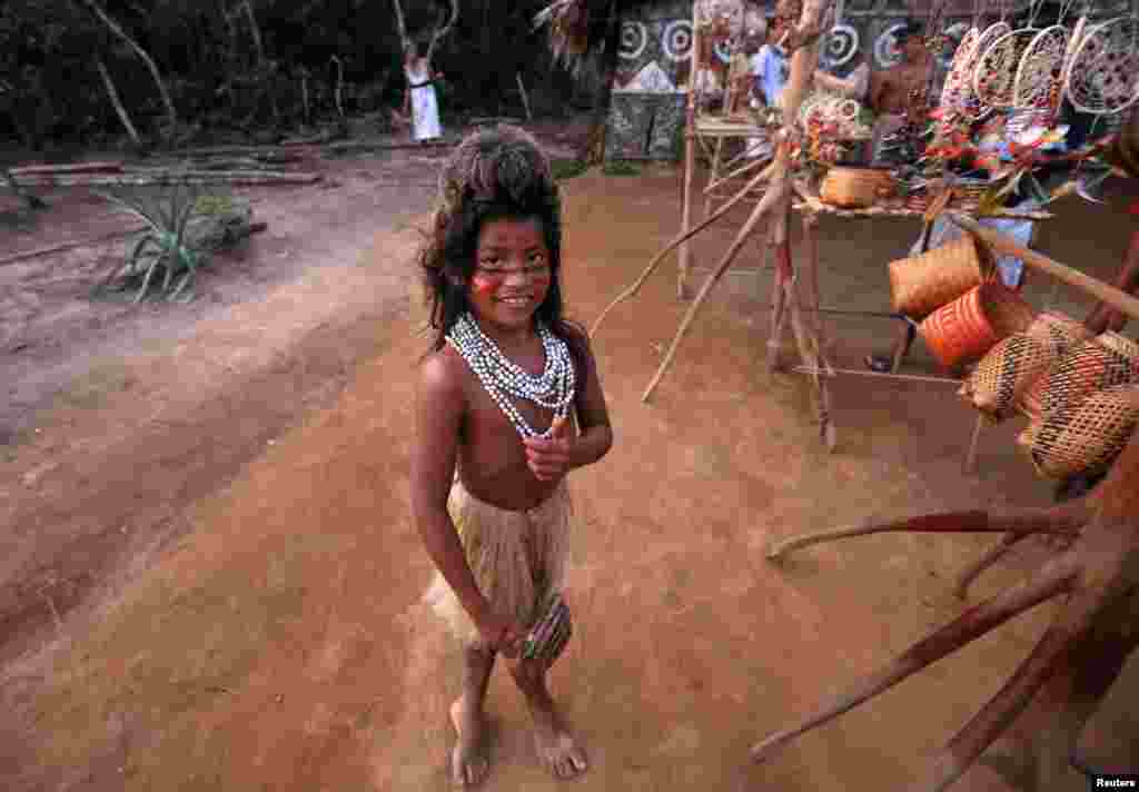 Seorang anak perempuan dari suku Tatuyo Amazon berpose sambil menunggu pernak-pernik yang dijualnya untuk turis di desanya di&nbsp;Rio Negro, Brazil, 23 Juni 2014. (REUTERS/Andres Stapff). 