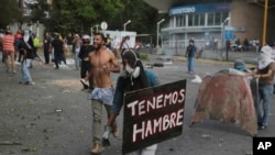 Un manifestante tiene un cartel que reza "Tenemos hambre". Lo lleva durante los frentamientos con la Guardia Nacional Bolivariana, en el municipio de El Hatillo, en las afueras de Caracas, Venezuela, el 2 de mayo de 2017.