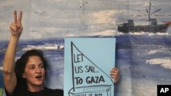 An activist holds a placard during a news conference regarding preparations of a flotilla, which is due to set sail to Gaza from Greece, in Athens, June 27, 2011