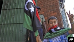 A child holds a Kingdom of Libya flag as a group of Libyans living in Zimbabwe demonstrate outside the Libyan embassy in the capital of Harare, August 24, 2011 (file photo)