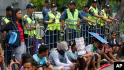 Polisi mengawasi para pengunjuk rasa di depan gedung Konsulat China, dalam aksi protes militerisasi Cina atas kawasan di Laut Cina Selatan yang disengketakan, di distrik keuangan kota Makati di timur Manila, Filipina, Sabtu, 21 Juli 2018. 