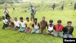 FILE - Ten Rohingya Muslim men with their hands bound kneel as members of the Myanmar security forces stand guard in Inn Din village, Sept. 2, 2017. 