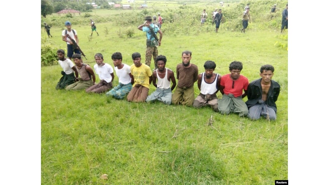 FILE - Ten Rohingya Muslim men with their hands bound kneel as members of the Myanmar security forces stand guard in Inn Din village, Sept. 2, 2017.
