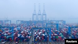 FILE - Containers and trucks are seen on a snowy day at an automated container terminal in Qingdao port, Shandong province, China, Dec. 10, 2018. 